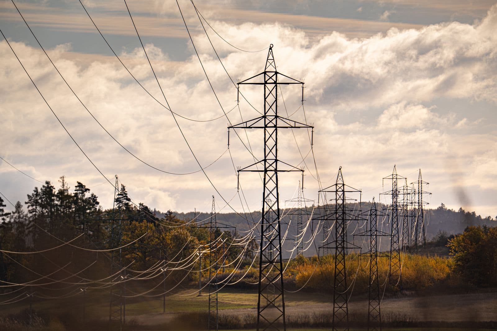 High-voltage electricity transmission pylons and power lines against a dramatic sky